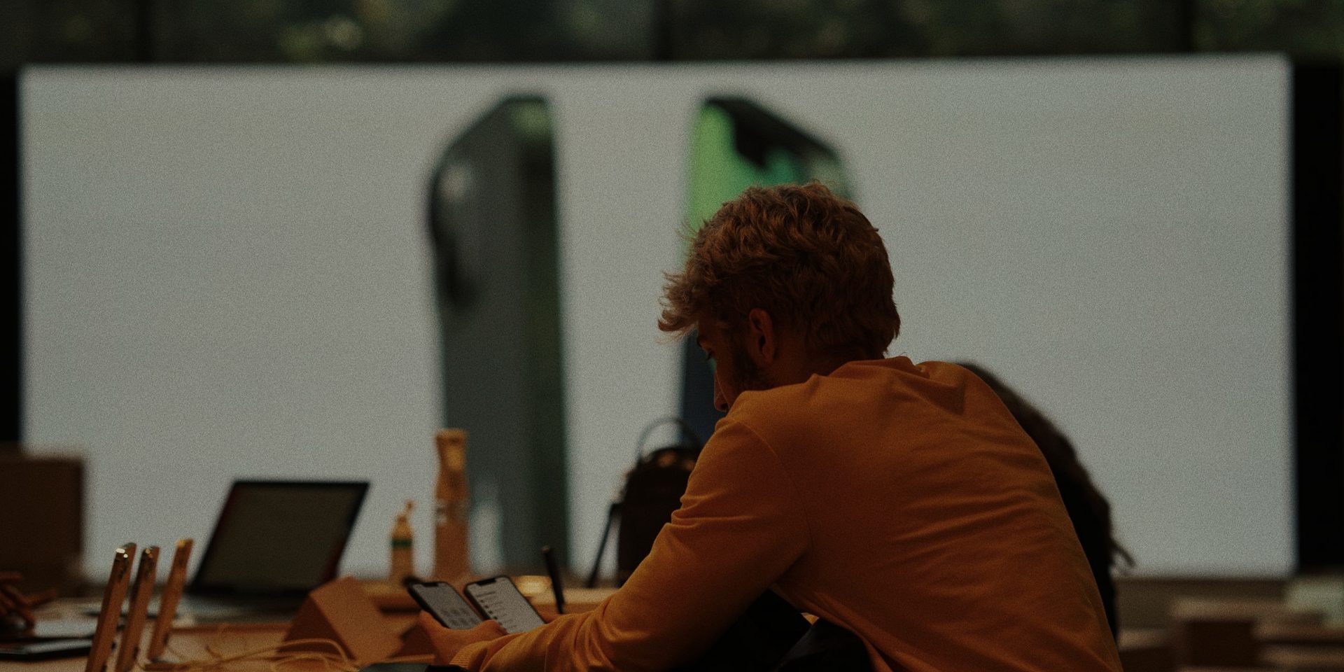 A customer trying smartphones at a lit display in a phone store.